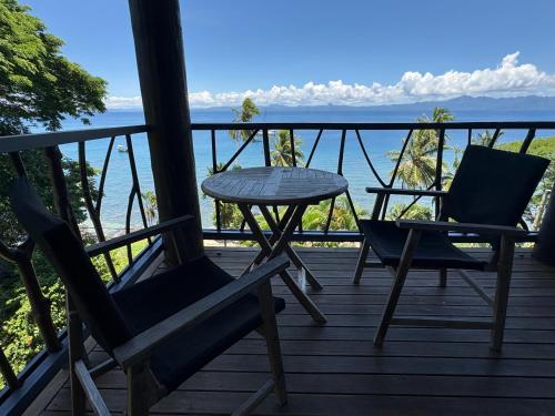 a porch with two chairs and a table and the ocean at Beachfront Villa - Pod House, Private Plunge Pool in Savusavu