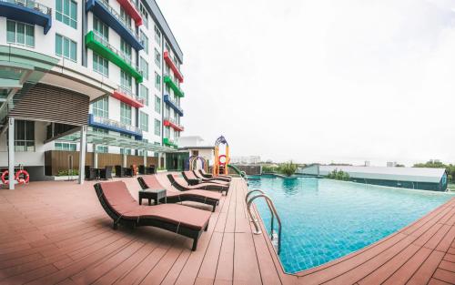 a swimming pool with benches next to a building at V8 Hotel Johor Bahru in Johor Bahru