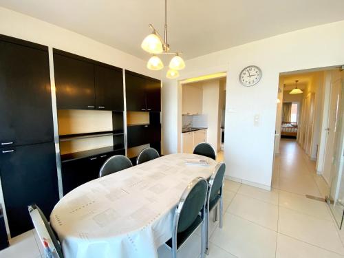 a dining room with a table and chairs and a clock at Attic Apartment Nieuwpoort near Beach in Nieuwpoort