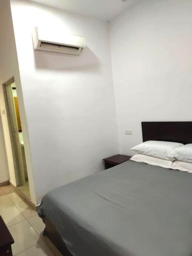 a white bedroom with a bed and a light on the wall at S&P Hotel in Tampin