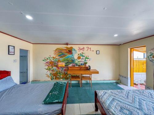 a room with two beds and a desk with a painting on the wall at Long Vĩ hotel - đảo Phú Quý in Cu Lao Thu