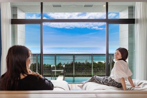 two women sitting on a couch in front of a window at KAMENOI HOTEL Kamogawa in Kamogawa