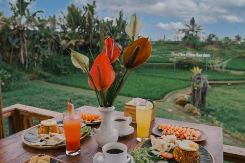 een houten tafel met eten, bloemen en drinken bij The Fire Flies Garden Villa in Penginyahan