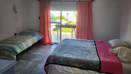 two beds sitting in a room with a window at Casa con piscina y jacuzzi en santa clara del mar in Santa Clara del Mar