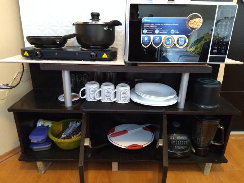 a table with a microwave and a stove with dishes at Loft con sala, desayunador y baño in Lomas de Angelopolis