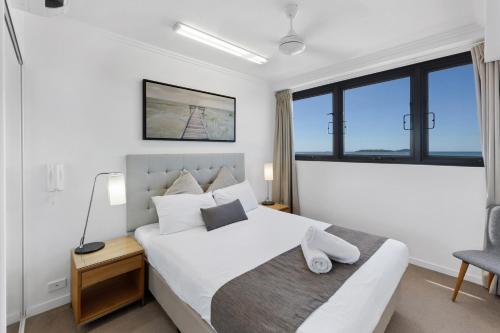 a bedroom with a white bed and a window at Pacific Sands Apartments Mackay in Mackay