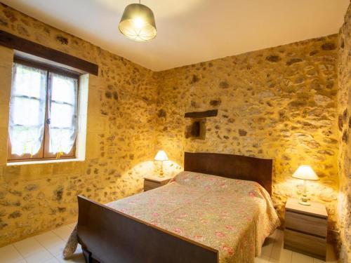 - une chambre avec un lit dans une pièce dotée de murs en pierre dans l'établissement Maison 3 chambres avec jardin à Domme - FR-1-616-48, à Domme