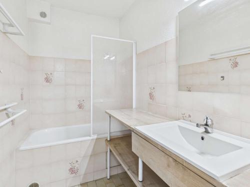 La salle de bains blanche est pourvue d'un lavabo et d'une baignoire. dans l'établissement Appartement 2 pièces à Marseillan-Plage avec Parking et Climatisation - FR-1-326-853, à Marseillan
