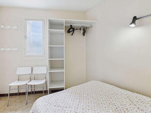 - une chambre avec un lit et deux chaises blanches dans l'établissement Appartement 2 pièces à Marseillan-Plage avec Parking et Climatisation - FR-1-326-853, à Marseillan