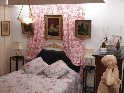 a bedroom with a bed with pink floral curtains at Charmant Studio avec Jardin et Terrasses, Environnement Calme et Historique - FR-1-583-383 in Mersuay