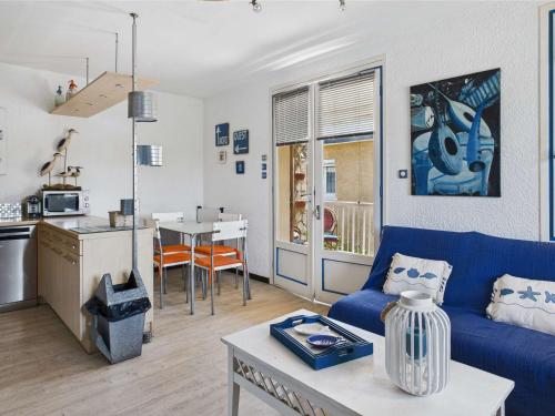 un salon avec un canapé bleu et une cuisine dans l'établissement Appartement 3 pièces avec terrasse à Marseillan-Plage - FR-1-326-858, à Marseillan