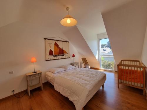 a bedroom with a bed and a window and a crib at Maison moderne 8 pers à St Gildas de Rhuys, près du bourg et falaises - FR-1-775-29 in Saint-Gildas-de-Rhuys