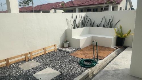 a garden with a hose on the ground next to a fence at Dedaun Homestay Perlis in Kangar