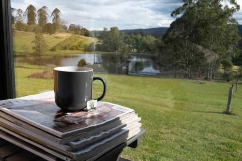 a coffee cup sitting on top of a stack of books at Little Enniskillen by Tiny Away in Kurrajong
