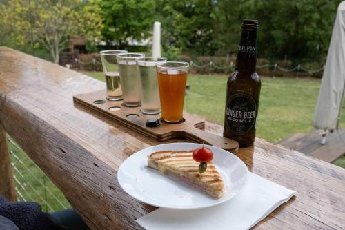 a table with a plate of food and glasses of beer at Little Enniskillen by Tiny Away in Kurrajong