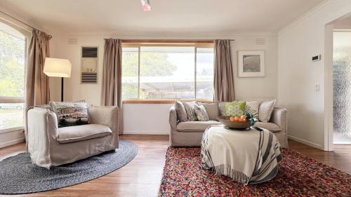 Una sala de estar con un sofá y sillas y una mesa. en Lucerne Escape by GoodLive, en Frankston