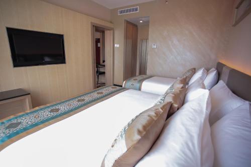 a hotel room with a bed with pillows and a television at V8 Hotel Johor Bahru in Johor Bahru