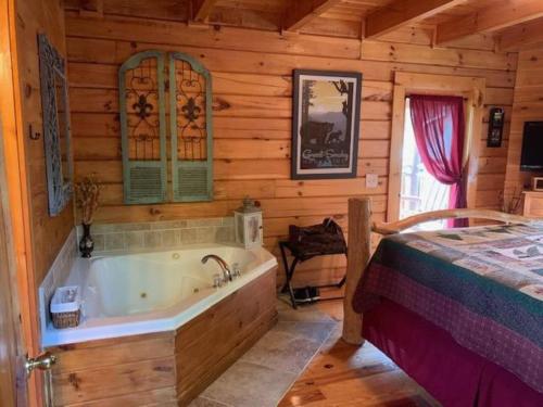 a bathroom with a bed and a tub in a cabin at Bearadise Romantic Swing MtnViews*Hottub Easy Road in Williamsburg