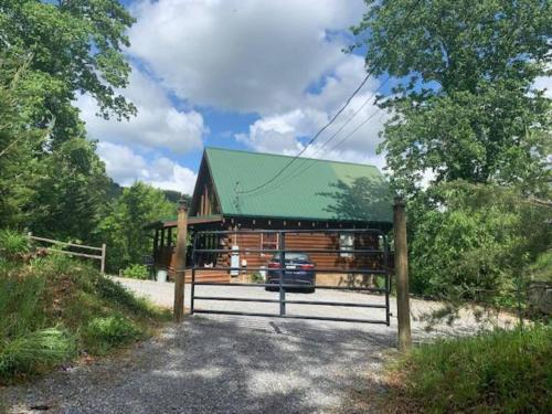 a wooden cabin with a green roof and a gate at Bearadise Romantic Swing MtnViews*Hottub Easy Road in Williamsburg