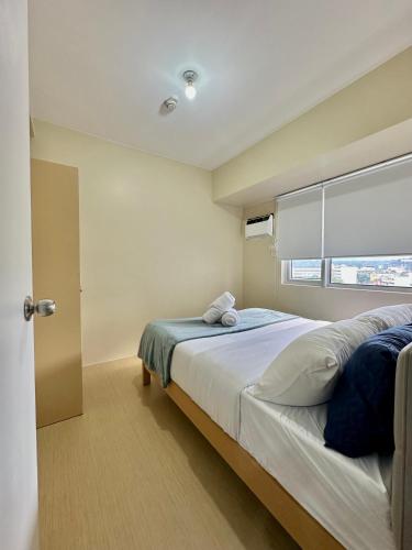 a bedroom with a large bed and a window at Pool View Cozy 1-Bedroom Unit Avida Aspira Tower 2 in Cagayan de Oro