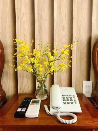 a telephone and a vase of yellow flowers on a table at Cozy 86 Homestay in Can Tho