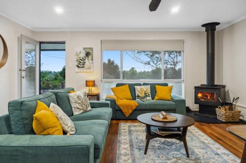 a living room with two green couches and a fireplace at Wattle Cottage - A Stylish Hinterland Escape in Maleny