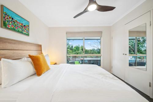 a bedroom with a white bed and a ceiling fan at Wattle Cottage - A Stylish Hinterland Escape in Maleny