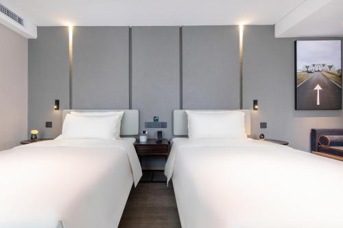 two beds in a room with white sheets at Atour Hotel Suzhou Guanqian Street Leqiao Station in Suzhou
