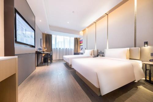 a hotel room with two beds and a flat screen tv at Atour Hotel Suzhou Guanqian Street Leqiao Station in Suzhou
