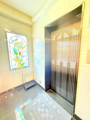 a bathroom with a shower with a door and a stained glass window at Tokyo Holiday Hotel in Tokyo
