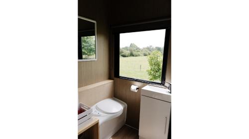 a small bathroom with a toilet and a window at Rural Delight by Tiny Away in Ohaupo