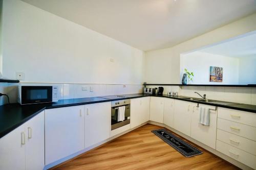 a kitchen with white cabinets and black counter tops at Serene Mountain Cabin Retreat Tamborine Mountain in Mount Tamborine