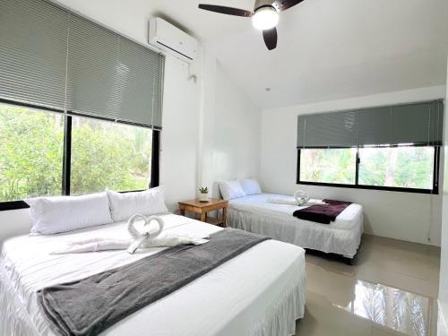 a bedroom with two beds and two windows at Taylors Plantacion Resort- Modern Villa in Alga