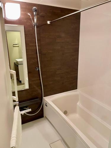 a bathroom with a bath tub and a mirror at Uhome Fabric Hotel in Tokyo