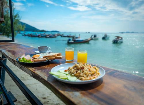 uma mesa com um prato de comida e dois copos de sumo de laranja em Anda Lipe Resort em Ko Lipe