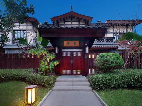 a house with a red door with a gate at Song Hotel Chengdu Qingcheng in Dujiangyan