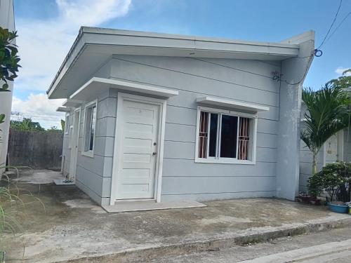 a small white house with a door and a window at The Bocol's House Stay in Sampong