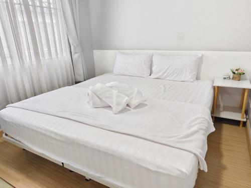 two beds in a room with white sheets and pillows at AuraHome282 in Khlong Luang