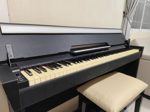 a black piano with a stool next to a window at AuraHome282 in Khlong Luang