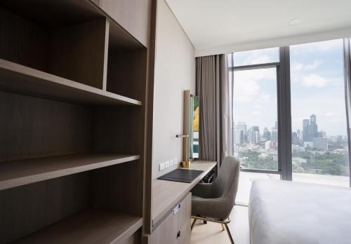 a bedroom with a bed and a desk and a window at Wyndham Bangkok Queen Convention Centre in Bangkok