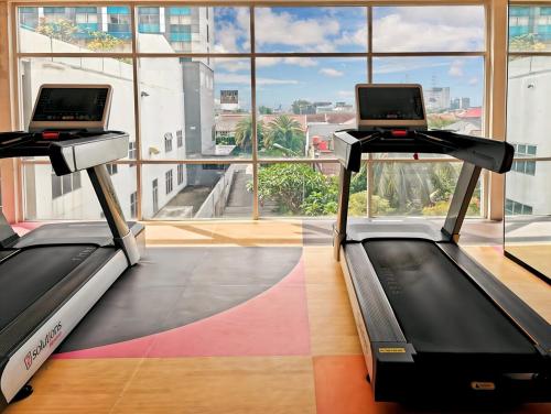 two treadmill machines in a room with a large window at Homy Studio Grand Caman Bekasi Jatibening with Pool in Cibening Empat