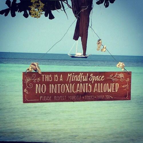 a sign on the beach with a person on a boat at Samma Karuna Beach & Wellness Resort - Intoxicants free in Haad Chao Phao