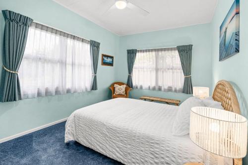 a bedroom with a white bed and two windows at Pacific Waves - Pet Friendly Original Beach House in Kingscliff