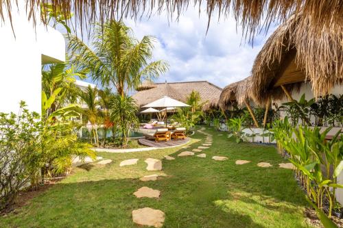 a backyard with a resort with a patio and grass at Uryah Hotel Lombok in Selong Belanak