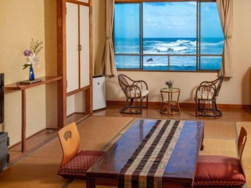 a living room with a table and chairs and a large window at Daitoku Hotel in Choshi