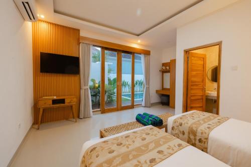 レギャンにあるArvi Villa Pandawa Legianのベッド2台と薄型テレビ付きのホテルの部屋