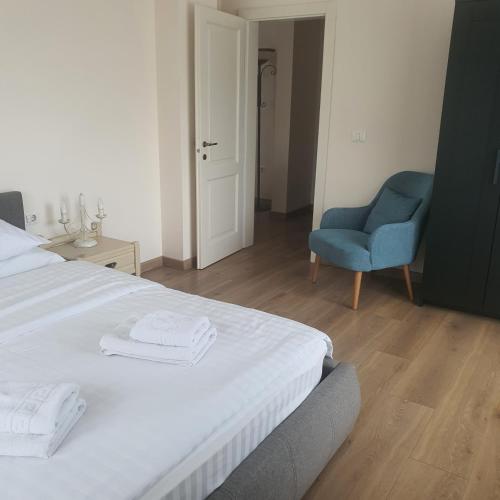 a bedroom with a bed and a blue chair at Bloom Apartament in Alba Iulia