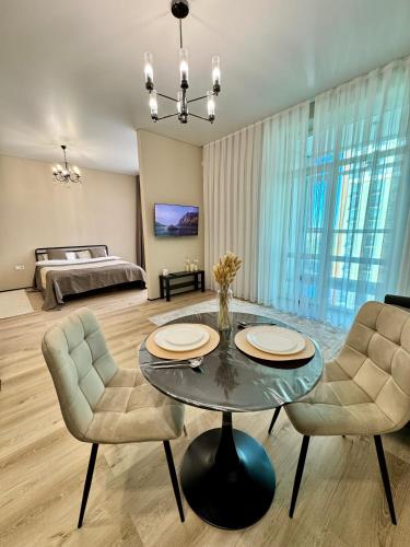 a living room with a table and chairs and a bed at A-Six Apartment ЖК Достар in Karagandy