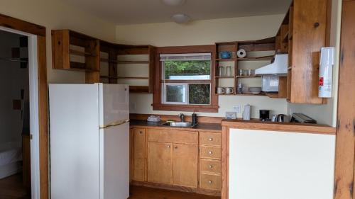 a kitchen with wooden cabinets and a white refrigerator at Seine Boat Inn in Alert Bay