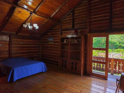 una camera da letto in una baita di tronchi con un letto e una finestra di Grand Saint Bernard Juayúa a Juayúa